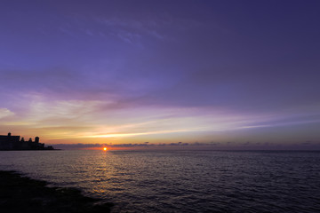 Fototapeta na wymiar Sunset over Malecon and Atlantic Ocean with Morro Castle in background - Havana, Cuba 