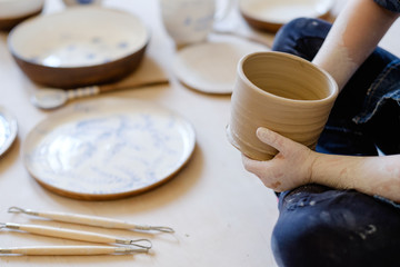 pottery workshop. young artisan hand holding a craft clay jug. handmade crockery concept