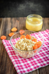 Oatmeal porridge with dried apricot, raisins and honey in bowl on dark wooden background. Healthy food for breakfast.