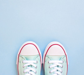 Pastel turquoise female sneakers on blue background. Flat lay, top view minimal background. Fashion blog or magazine concept.