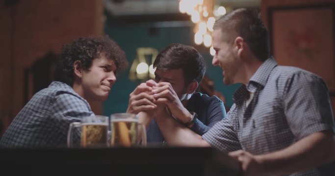 old friends doing armwrestling in pub then drinking beer 4k dollyshot