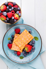 Fresh berry salad on blue dishes. Vintage wooden background.