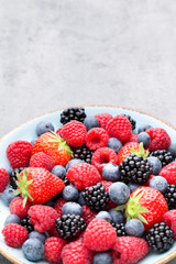 Fresh berry salad on blue dishes. Vintage wooden background.