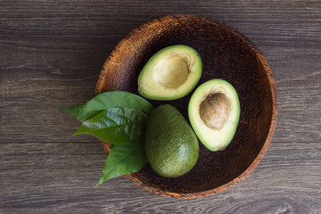 Healthy food. Cut avocado in a brown bowl on a wooden background