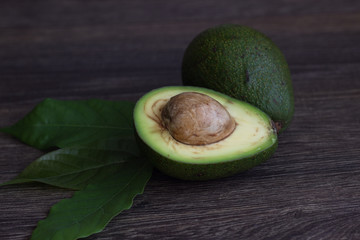 Avocado halves on wooden background. Dietary food, concept of vegetarian food. Copy space.