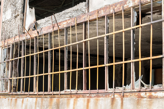 Close Up Of Metal Safety Bars On The Windows Of Small House Damaged Walls With Bullet Holes Used As Improvised Hidden Prison In The War Zone By Terrorists In The Syria, Selective Focus