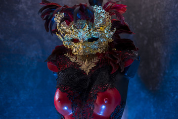 Red golden venetian carnival mask with feathers  on a draped red velvet theater curtain. Mask in the dark
