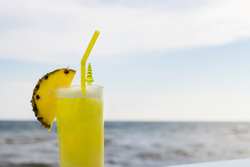 Pineapple fruits drink on beach background.