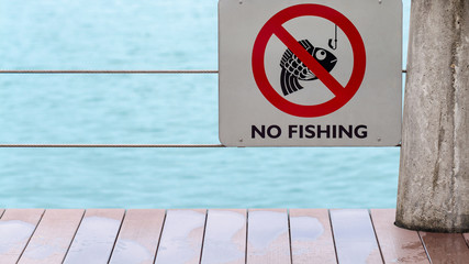 no fishing sign on fence by river or lake after rain with wet floor