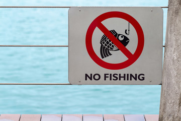 no fishing sign on fence by river or lake