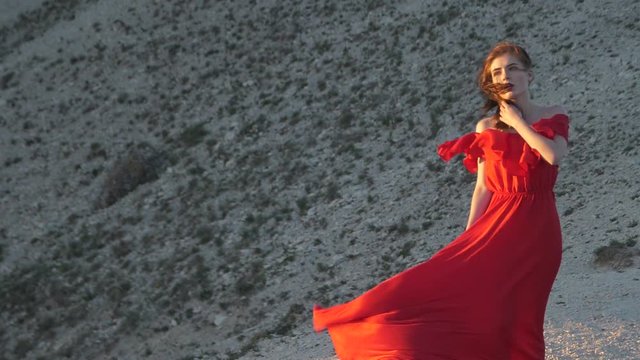 Young woman in red tunic looks at sun Blowing wind