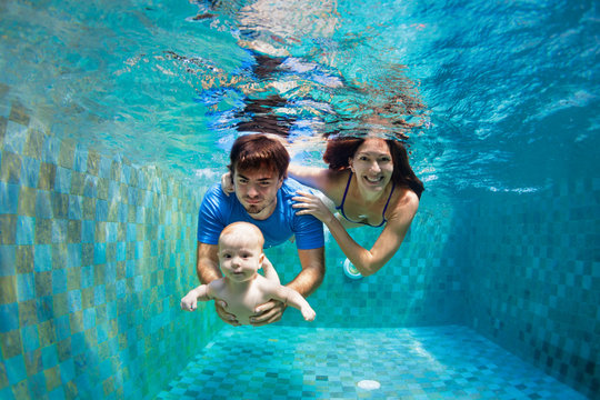Happy family - mother, father, baby son learn to swim, training to dive underwater with fun in pool to keep fit. Healthy lifestyle, active parent, people water sport activity, kids swimming lessons