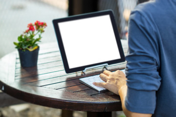 Woman is using a tablet and typing keyboard in the garden.