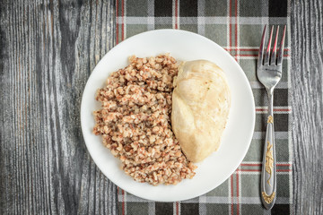 Boiled chicken breast and buckwheat on grey wooden background. Healthy lunch or dinner.