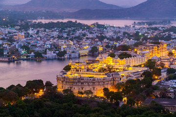 Naklejka premium Udaipur city at lake Pichola in the evening, Rajasthan, India. View from the mountain viewpoint see the whole city reflected on the lake.