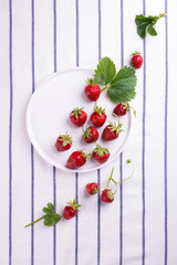 Fresh red strawberry in a bowl with green leaf on white background. Top view