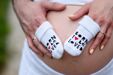 Naklejka premium A pregnant woman and a man holding his stomach. The concept of waiting for the birth of a child.