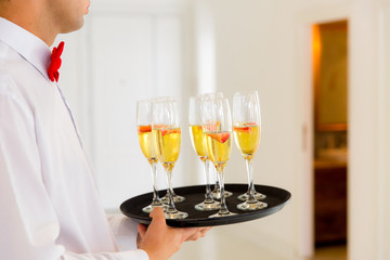 Waiter With Red Bow Standing With Champagne Glasses And Strawberries