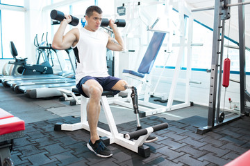 Fototapeta na wymiar Young amputee man doing exercises in gym
