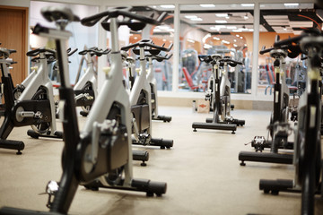 Several fitness bicycles for visitors of leisure center and instructor in gym