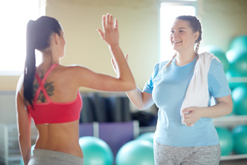 Young coach and one of her trainees going to make high five expressing success