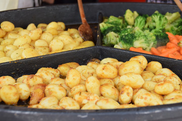 new potatoes and young vegetables fried on a stone pan outside