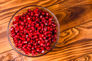 Seeds of the garnet fruit in glass bowl on wooden table. Top view