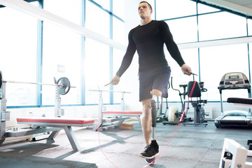 Young male disabled athlete skipping rope in gym