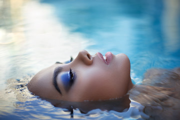 Beautiful long hair female model posing in the pool, outdoor portrait