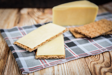 Crispbread with cheese on wooden background.