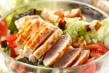 salad cesar with chicken grill in glass bowl on white wooden table. Decor fresh vegetables