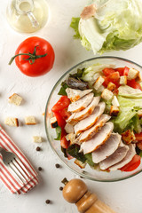 salad cesar with chicken grill in glass bowl on white wooden table. Decor fresh vegetables