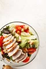 salad cesar with chicken grill in glass bowl on white table. Top view. Flat lay. Copyspace