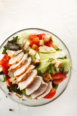 salad cesar with chicken grill in glass bowl on white table. Top view. Flat lay. Copyspace