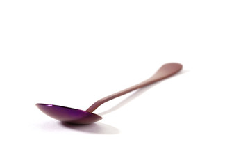Colorful purple stainless steel spoon isolated on white background  - focus on foreground with shallow depth of field