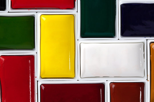 Colorful watercolor pans arranged in jigsaw puzzle top view with copy space