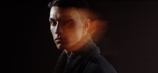 Side view of attractive brunette man with blurred face on dark studio background, close up