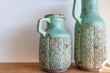 Two decorative vases on wooden table against white wall close-up