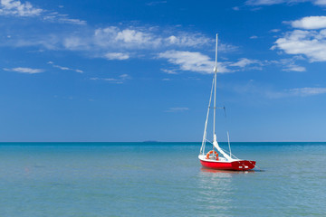 The small yacht is moored on the calm sea. The photo has plenty of place for your text.