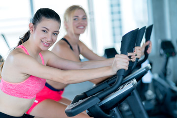 Fototapeta na wymiar attractive caucasian girlfriend happiness time in gym workout on stationary bicycle with smile and fresh