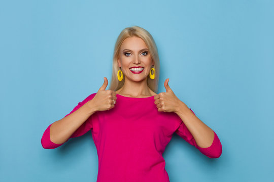Smiling Blond Woman Is Showing Thumbs Up And Looking At Camera