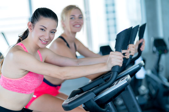 attractive caucasian girlfriend happiness time in gym workout on stationary bicycle with smile and fresh