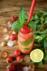 Lemonade with strawberry, lime, ice cubes and mint in a glass bottle