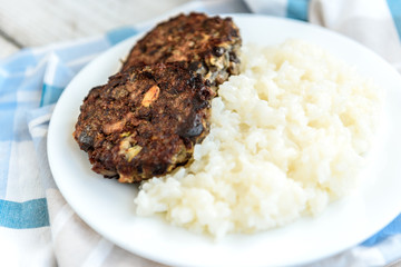 Homemade mushroom cutlets with rice porridge on wooden background. Healthy food for lunch or dinner.