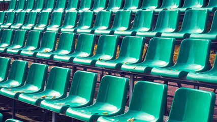 Empty green plastic chairs in a row at the stadium