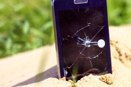 A nail in an old phone, it's punched. In the background a new phone
