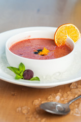 Side view - berry-fruit mousse served in bowl with an orange slice of berries and mint and ice slices. Dessert of the restaurant
