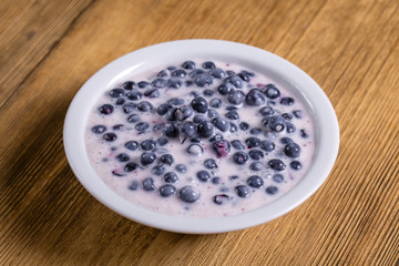 Fresh, ripe forest blueberries with sour cream and honey in white plate
