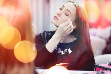 A young girl does make-up in a beauty salon. The girl in front o