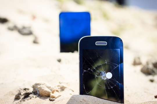 A nail in an old phone, it's punched. In the background a new phone